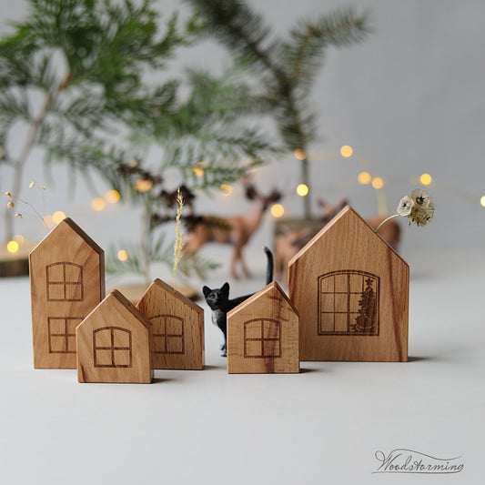 Five small wooden house-shaped ornaments with engraved window designs.