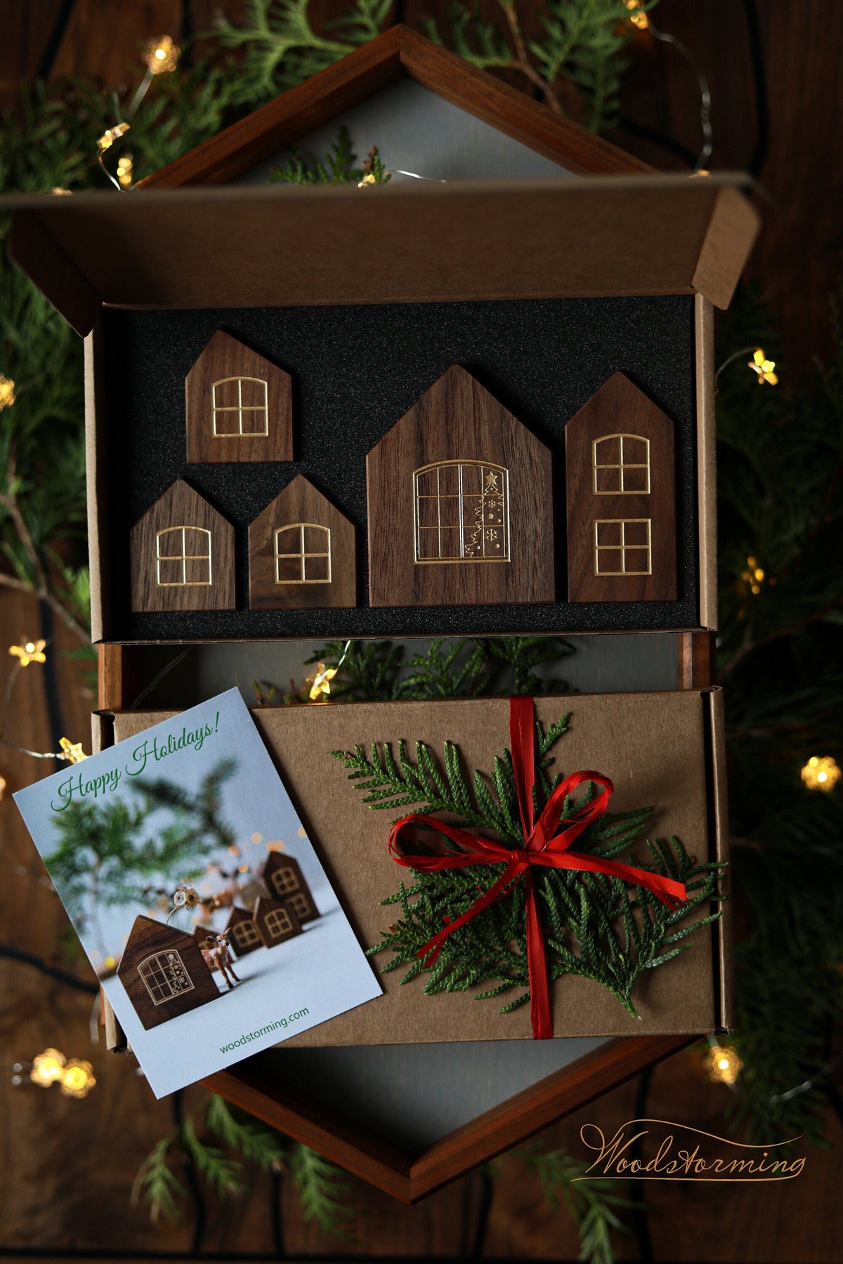 Handmade wooden Christmas village decoration displayed in a box with a red ribbon, consisting of five miniature houses.